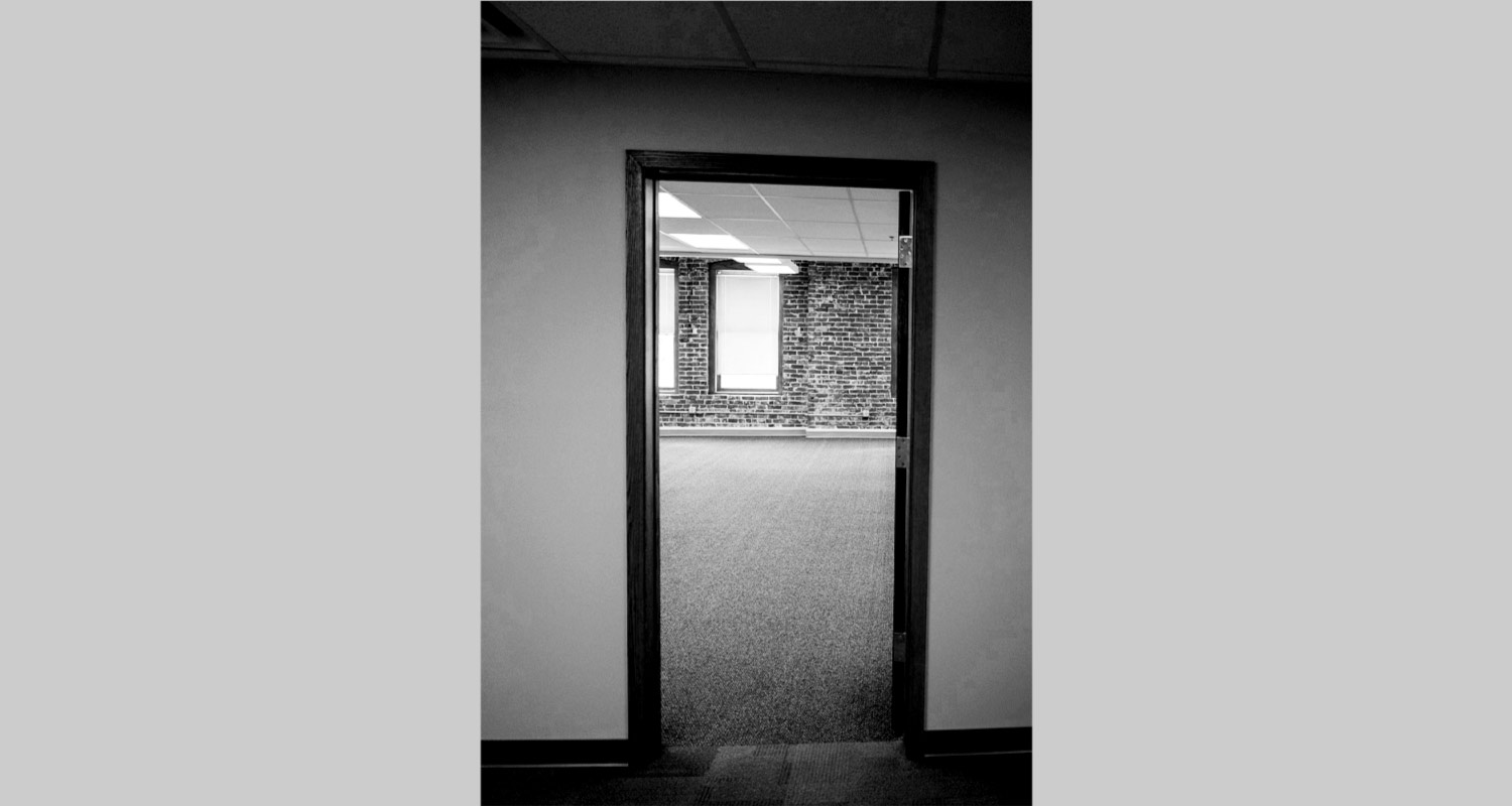 Outside view of entrance to large open office space 207, brick wall shown in distance