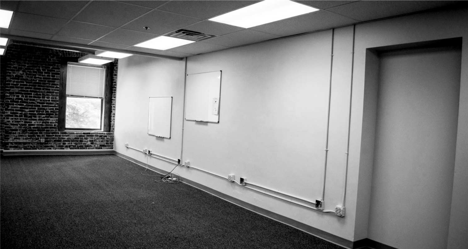 Large open office space 207 with exposed brick wall, pre-installed whiteboards, and O street facing windows